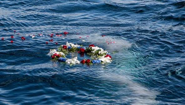 An illustrative floral wreath floating on the sea after a memorial farewell